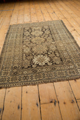 Vintage Caucasian rug corner, showcasing starburst and pawn motifs in charcoal, ivory.