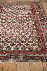 Vintage Caucasian rug showing reciprocating geometric splayed floral motifs in ivory, deep blush, and gray.