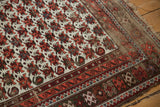 Geometric wine red and ivory borders on a vintage Caucasian rug with tattered edge.