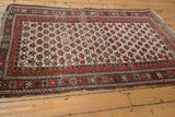 Worn, tattered end of Caucasian rug, featuring wine red and charcoal geometric borders.