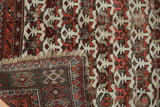Vintage Caucasian rug's corner reveals worn geometric field, tattered fringe, and dark green reverse.
