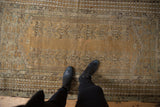Antique Kula rug displaying double column plant motifs, worn texture, and feet.
