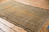 Beige field of antique Kula rug showing germinating plant motifs and classic layered borders.