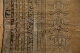 Close-up of an Antique Kula rug's worn pile, showing muted beige, charcoal, and gold pearl motifs.