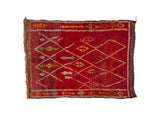 Vintage Moroccan hand-knotted rug with deep red field, white lattice, and primitive motifs.