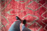 Shaggy pile texture of a vintage Moroccan carpet with abrashed raspberry red and grey diamonds.