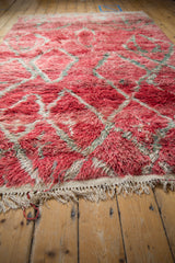 Shaggy red pile, geometric pattern, and ivory fringe on a vintage Moroccan carpet corner.
