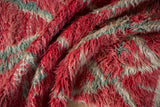 Hand-knotted foundation and shaggy, abrashed pile of a red and silver Moroccan rug.