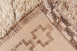 Thick antique ivory pile on vintage Moroccan rug, showing woven geometric coffee brown back.