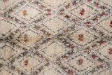 Textured ivory Moroccan rug pile with charcoal geometric outlines and colorful scattered motifs.