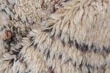 Thick, shaggy ivory pile with charcoal specks and subtle red tones on a Moroccan rug.