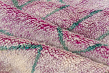 Thick, shaggy pile of Moroccan rug blending violet, aubergine, silver, and teal geometric lines.