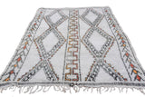 Ivory Moroccan carpet detail: charcoal diamond panel and colorful germinating plant motifs.