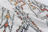 Thick pile of a vintage Moroccan carpet, displaying abstract ivory, charcoal, rust, and saffron patterns.