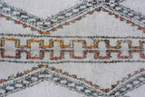Vintage Moroccan carpet: shaggy ivory pile, geometric rust, saffron, and charcoal design.