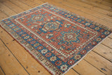 Vintage Karaja rug corner, showing brick red, indigo blue geometric border, and intact side cord selvage.