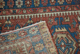 Vintage Karaja rug's folded corner reveals worn brick red, indigo geometric pattern, and hand-knotted reverse.