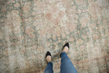 Distressed Sparta carpet's worn texture and floral vinery in muted ivory, green, raspberry tones.