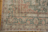 Distressed Sparta carpet corner shows faded ivory, raspberry, green floral motifs.