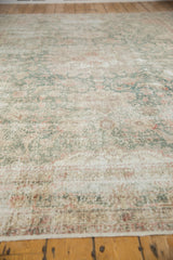 Distressed Sparta carpet's worn pile texture, showing faded green and blush floral vinery.