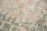Distressed pile texture showing faded ivory, ocean green, and raspberry floral vinery.
