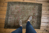 Faded pink floral bouquets with oxidized bronze tones on a distressed Karabagh rug.