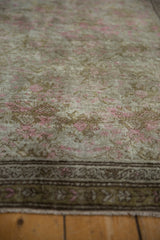 Distressed Karabagh rug: worn pink and bronze floral motifs with germinating plant border.