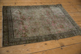 Distressed vintage Karabagh rug corner, pink floral bouquets, oxidized field, meandering vine border.