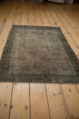 Distressed Karabagh rug corner: faded pink floral bouquets, detailed bronze borders, and even wear.