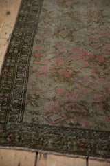 Distressed vintage Karabagh rug border with meandering vine and pink floral motifs.