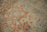 Close-up of distressed Persian Mahal rug with scrolled floral patterns in terra cotta and dusty blue.