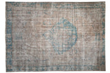 Vintage distressed Oushak carpet with a large, asymmetric turquoise medallion on a silver and brown field.