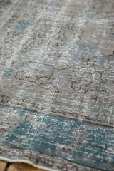 Evenly worn texture of a distressed Oushak carpet with visible knots in silver and turquoise.