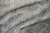 Distressed woven texture of a vintage Oushak carpet with silver, brown, and dusty turquoise hues.