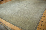 Distressed vintage Oushak carpet corner with wide banded border and faded geometric motifs.