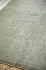 Distressed Oushak carpet's pile, showing muted ivory large scale motifs and side selvage.