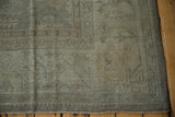 Corner detail of distressed Oushak carpet, showing muted beige geometric patterns and even wear.