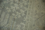 Distressed vintage Oushak rug pile showcasing muted tree-of-life motifs and banded border.