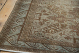 Distressed vintage Sivas rug corner, geometric coffee brown border, subtle blue motifs.