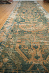 Detailed view of Hamadan runner's distressed texture, geometric scrolling leaves, dusty green and sand.