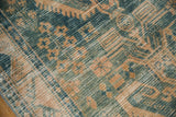Distressed Hamadan rug close-up, dusty ocean green, beige geometric patterns, exposed foundation.