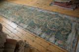 Distressed vintage Hamadan runner showing geometric floral pattern in dusty ocean green and sand tones.