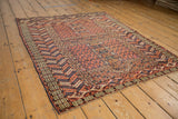 The intricate geometric layout of an antique Turkmen Hatchli rug, seen from a low perspective.