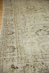 Distressed Oushak rug border revealing faded vinery patterns in ivory and chocolate brown.