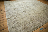 Distressed Oushak rug showing faded ivory, brown, and silver floral vinery details.