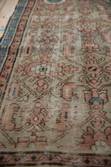 Distressed vintage Hamadan runner texture close-up, showing faded terracotta Herati pattern and blue border.