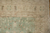Textured corner of a distressed vintage Sparta rug showing sea foam green and brown floral patterns.
