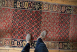 A person's view of the even wear and color abrash on a vintage red Turkish Oushak runner.
