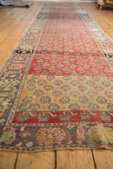 Perspective view down the length of a distressed Oushak runner, showing its staggered floral pattern and color variations.