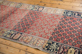 Angled view of a vintage Oushak runner showing the flow of its repeating pattern and color abrash.